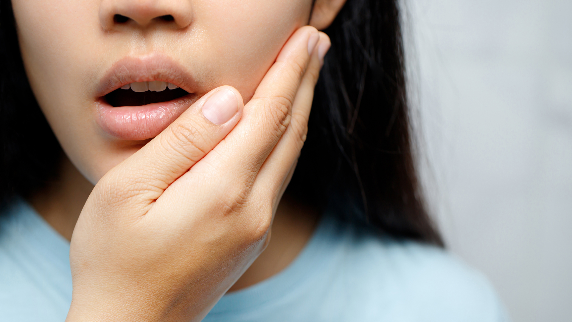 A woman is holding her face in pain because of a toothache.