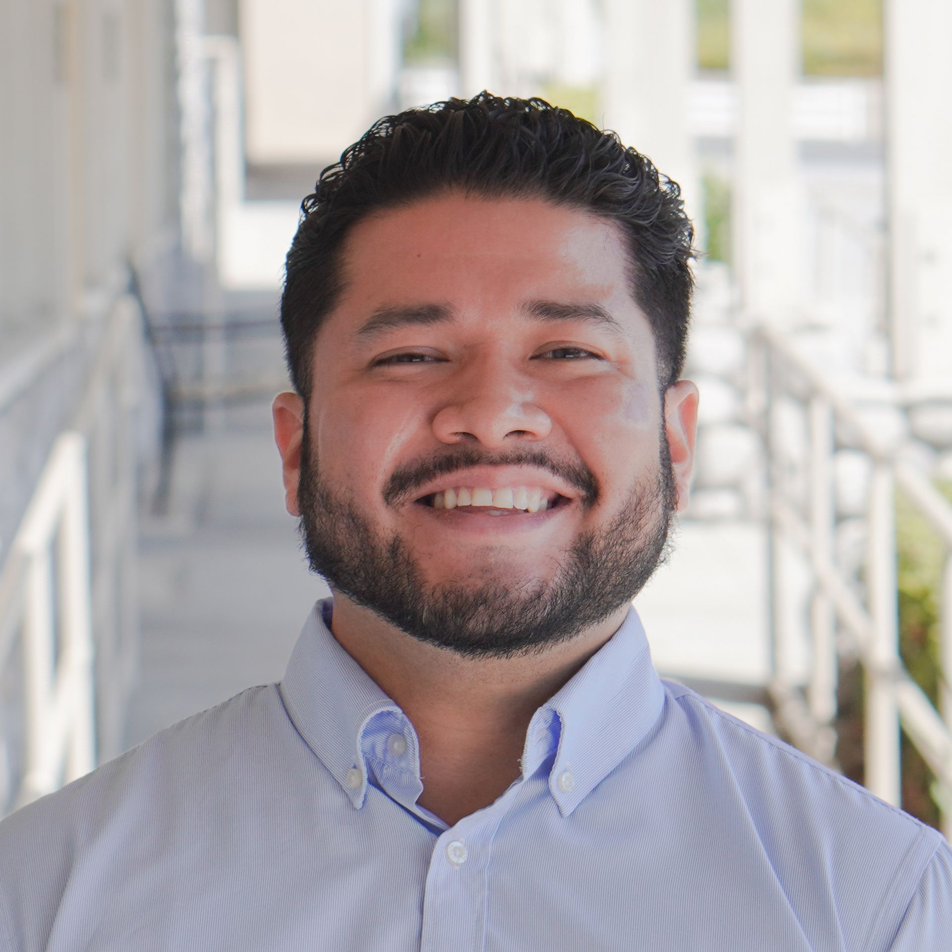 A man with a beard is smiling for the camera while wearing a striped shirt.