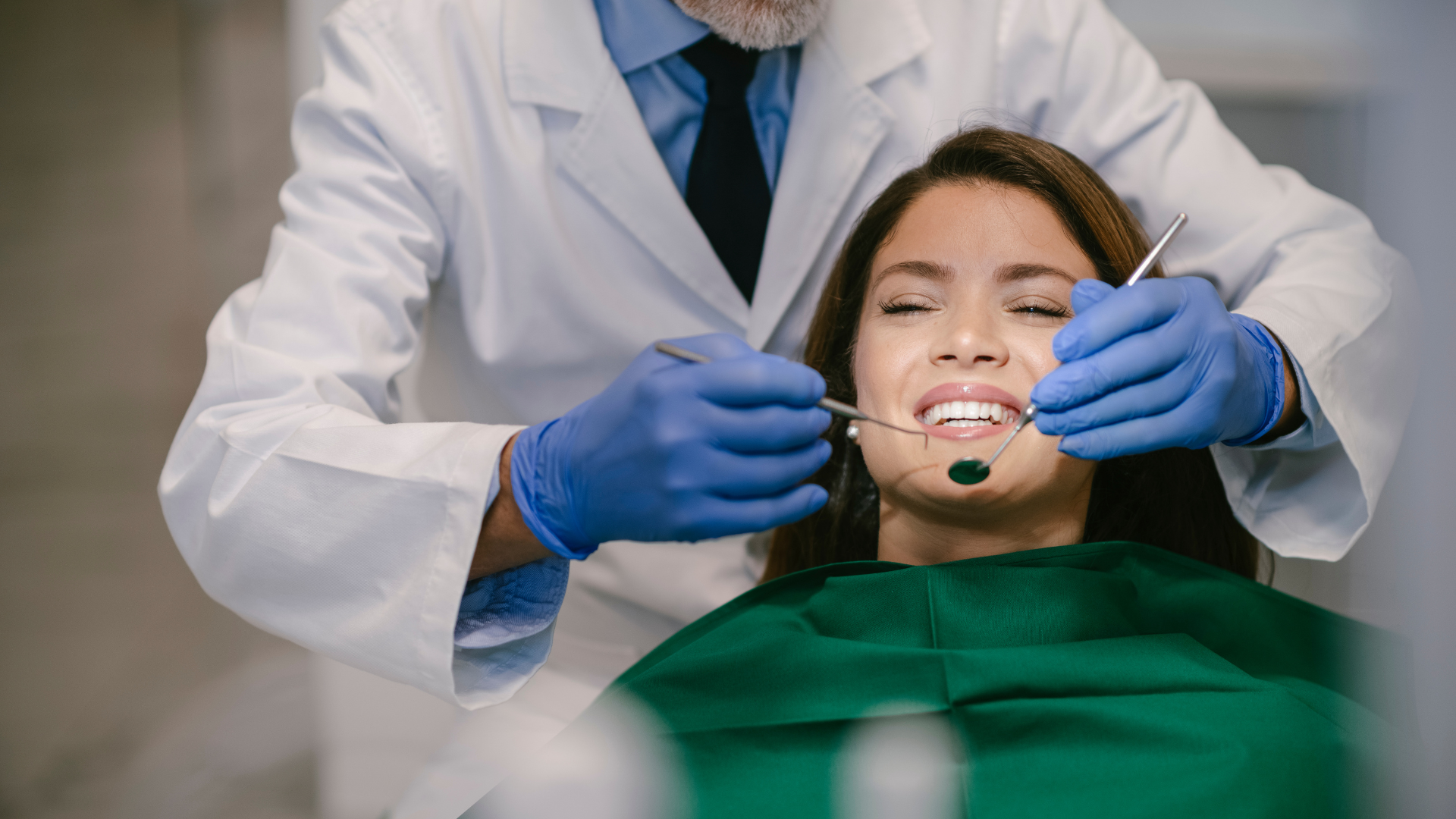 A dentist is examining a woman 's teeth in a dental office.