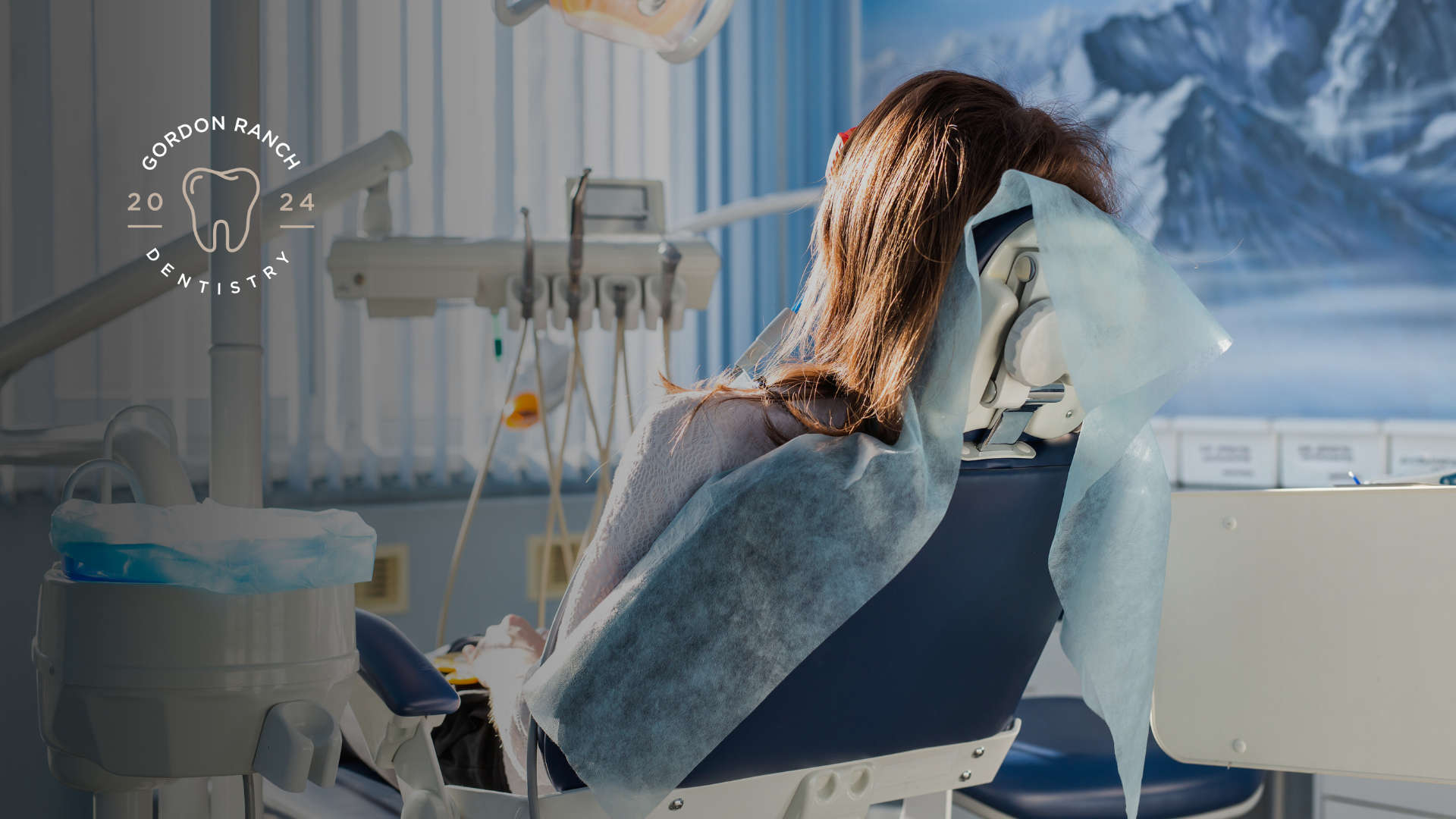 A woman is sitting in a dental chair in a dental office.