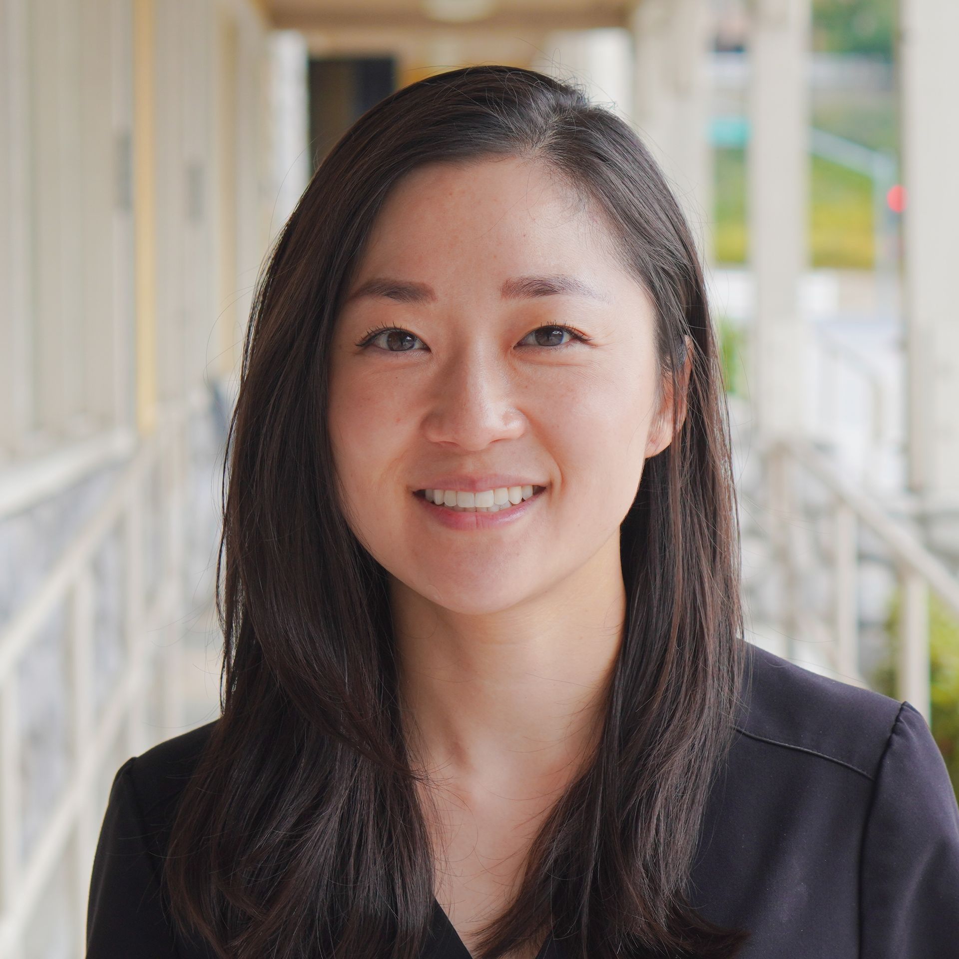 A woman with long dark hair is smiling for the camera.