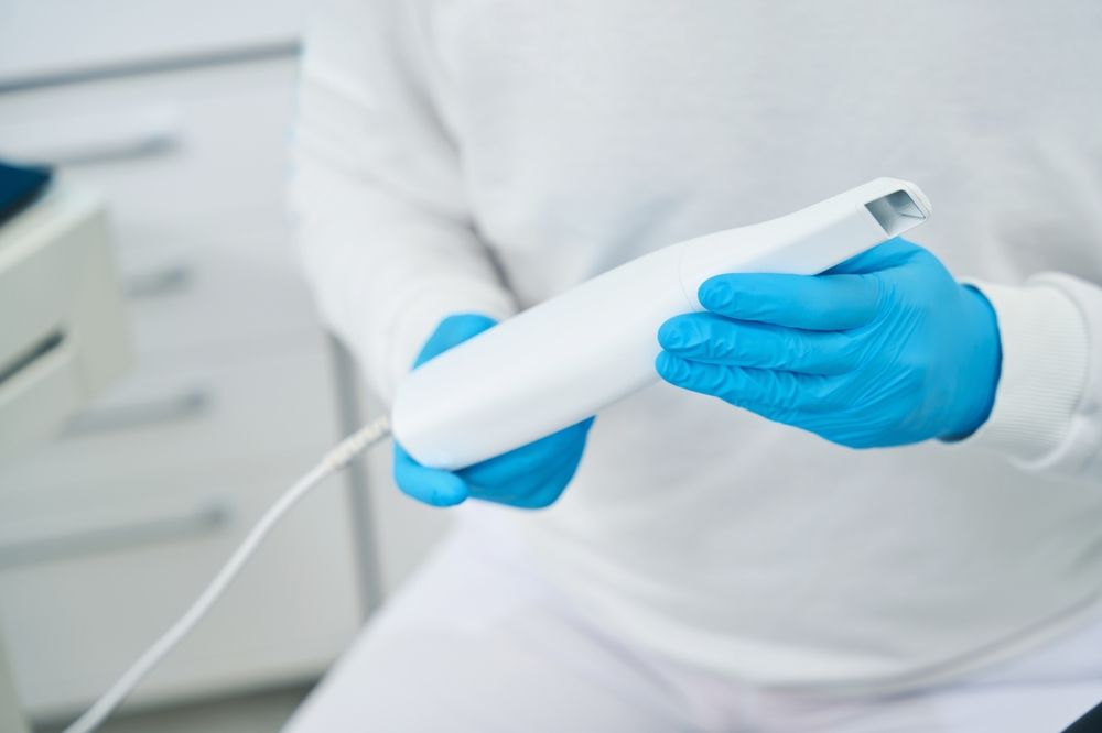 A person wearing blue gloves is holding a white object in their hands.