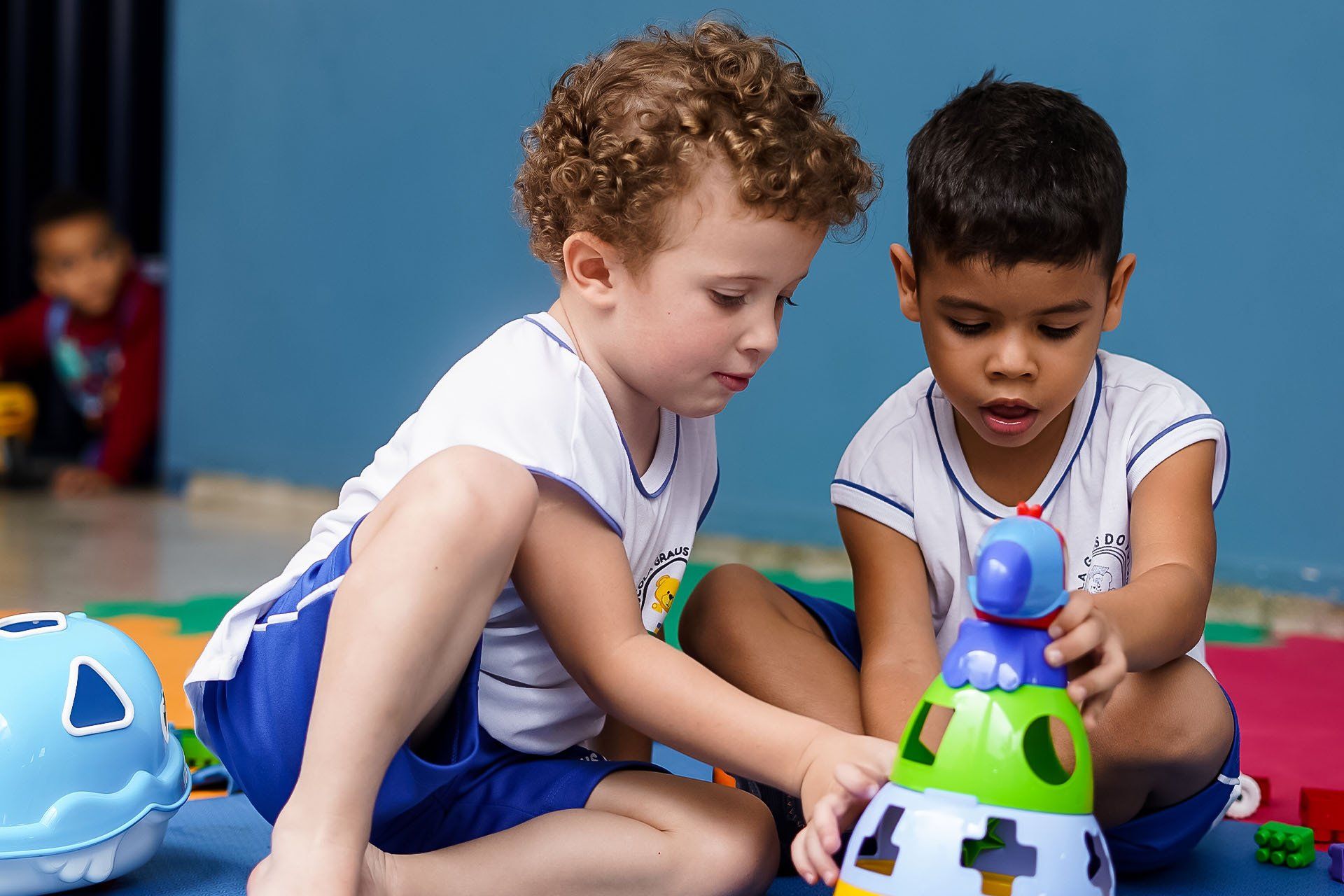 Dois meninos estão sentados no chão brincando com brinquedos.