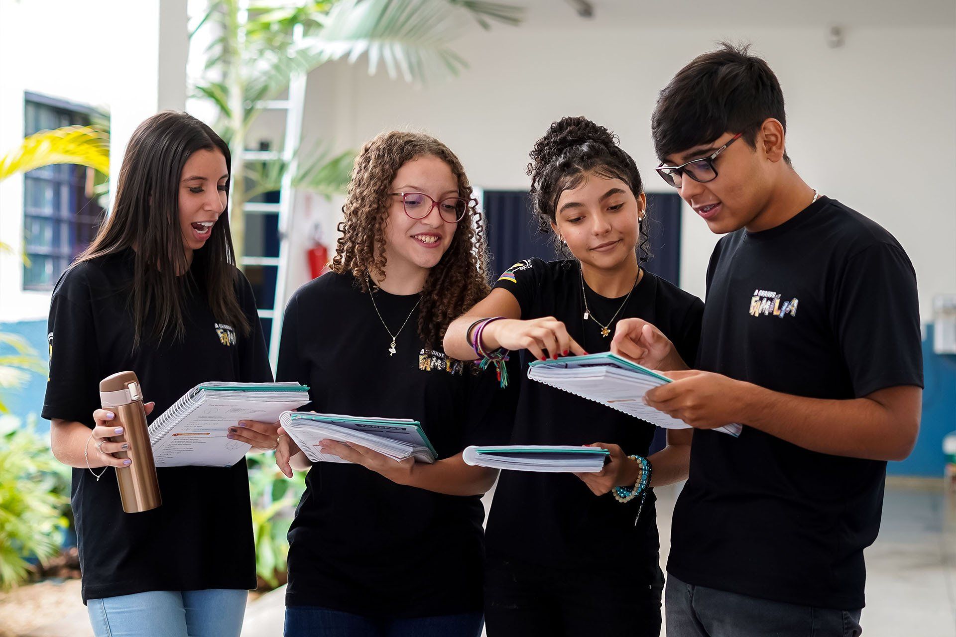 Um grupo de jovens estão de pé, um ao lado do outro, estudando.