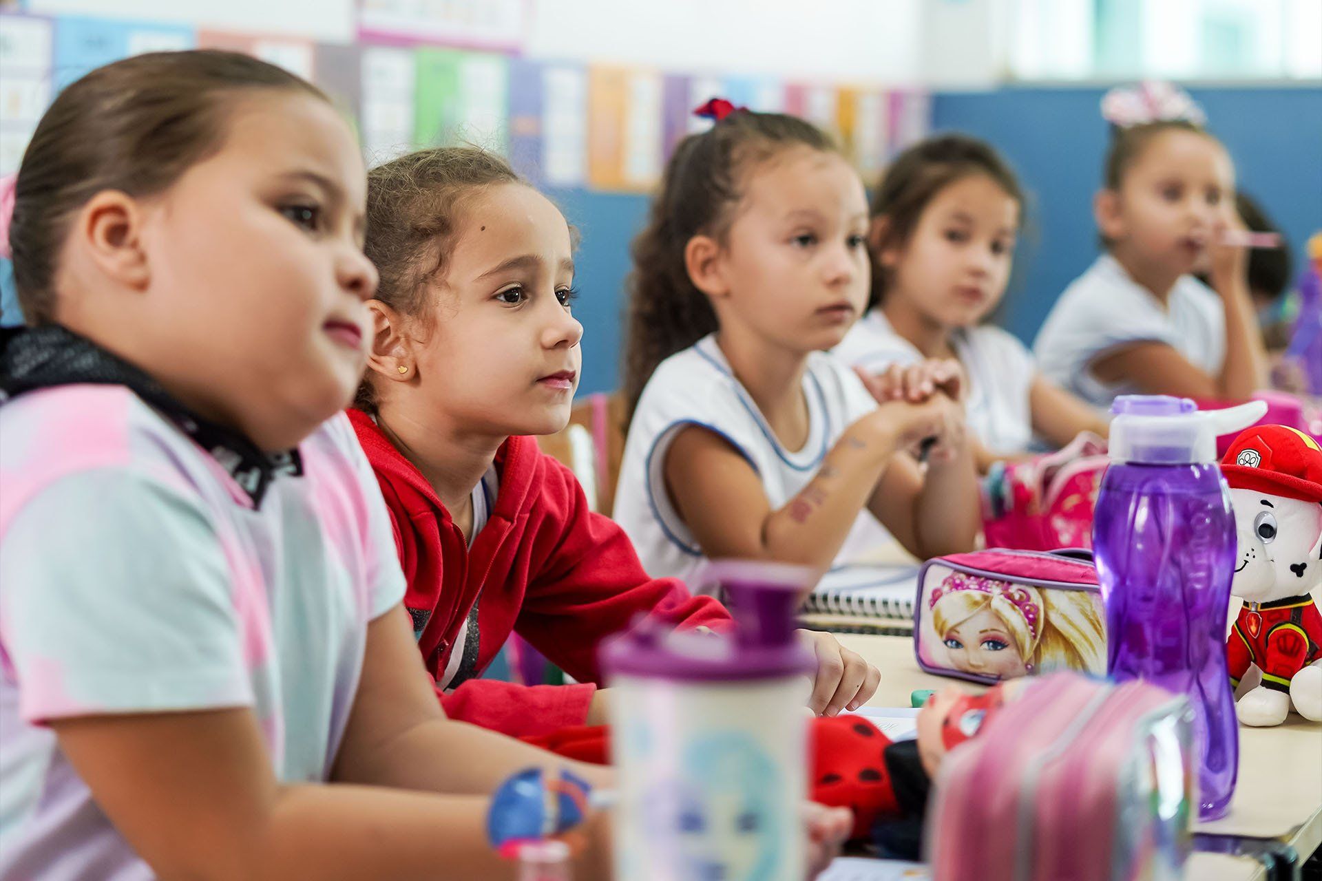 Um grupo de meninas está sentado à mesa em uma sala de aula.