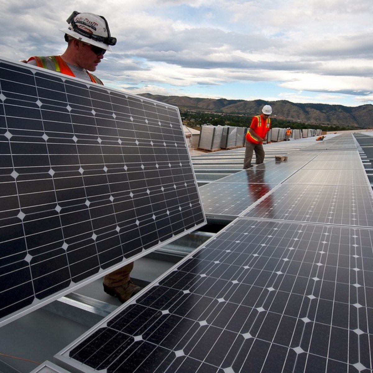 Two men are working on a roof with solar panels