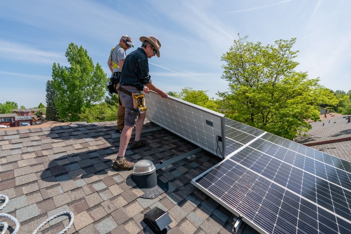 Two men are installing solar panels on a roof.
