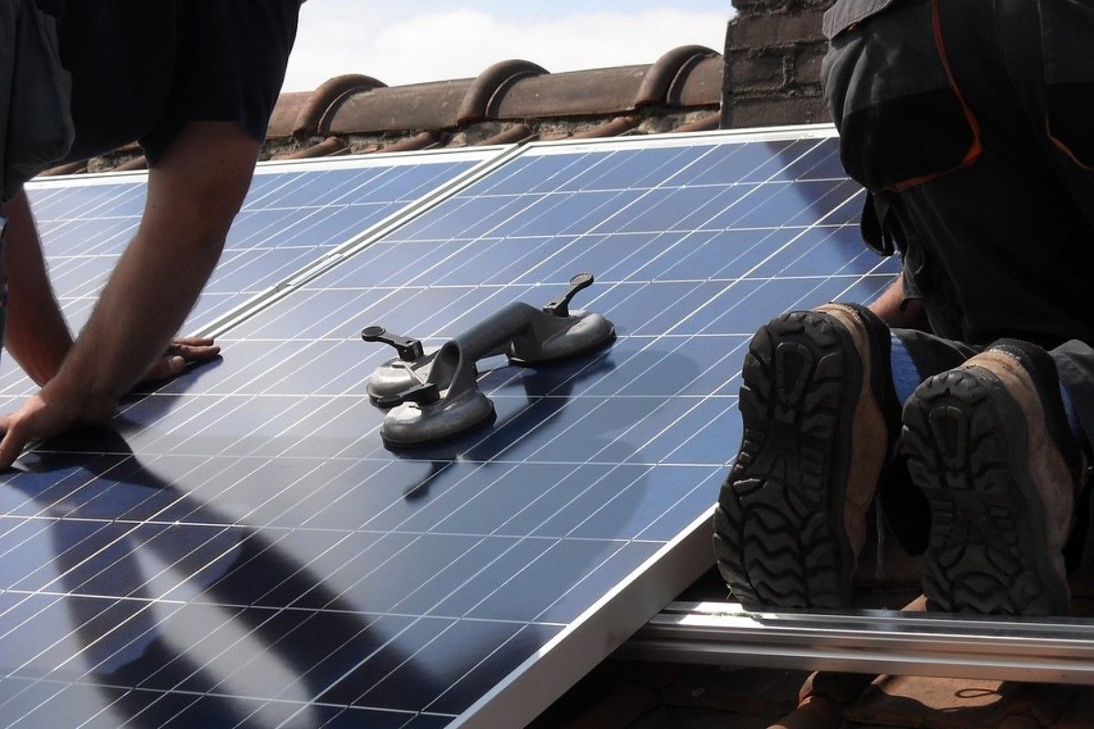 Two men are installing solar panels on a roof