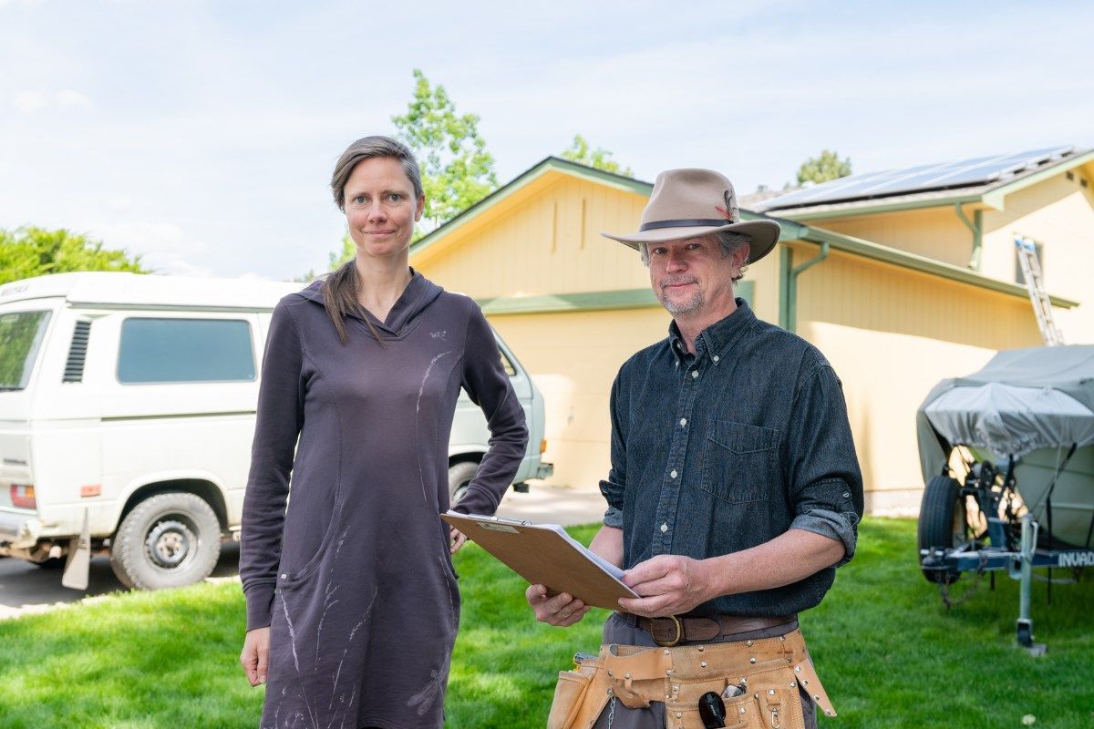 A man and a woman are standing next to each other in front of a house.
