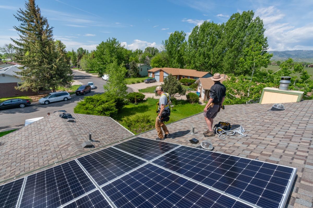 Two men are installing solar panels on the roof of a house.