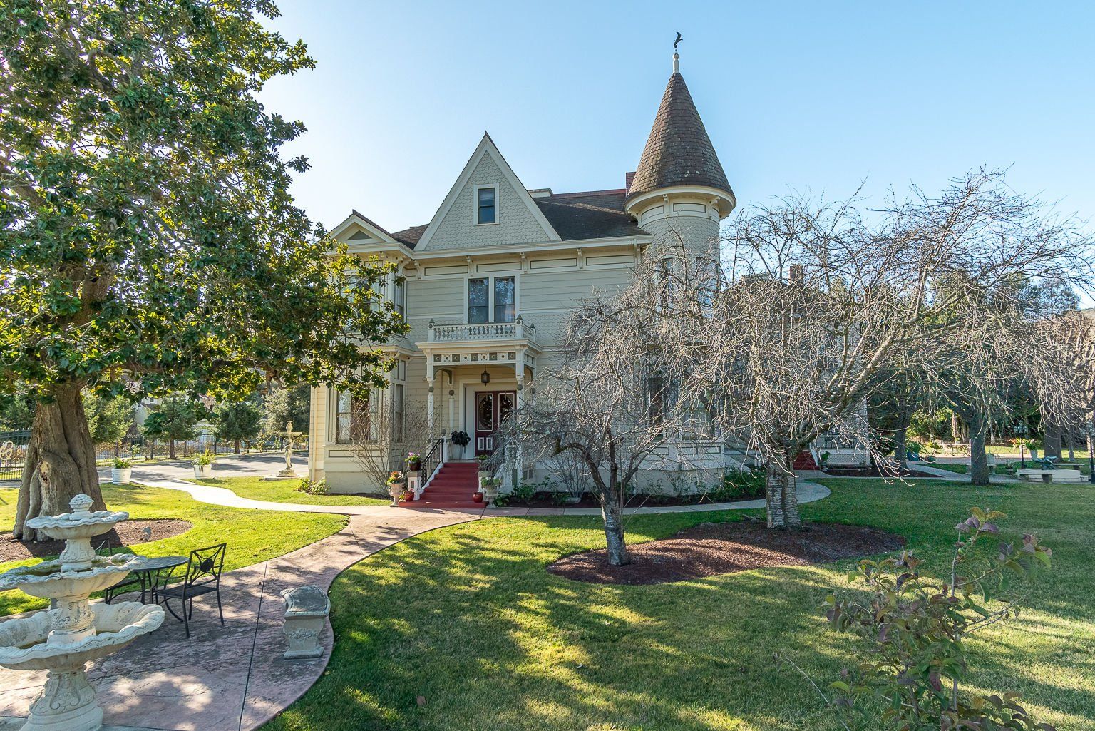 A large house with a tower on top of it is surrounded by trees and grass.