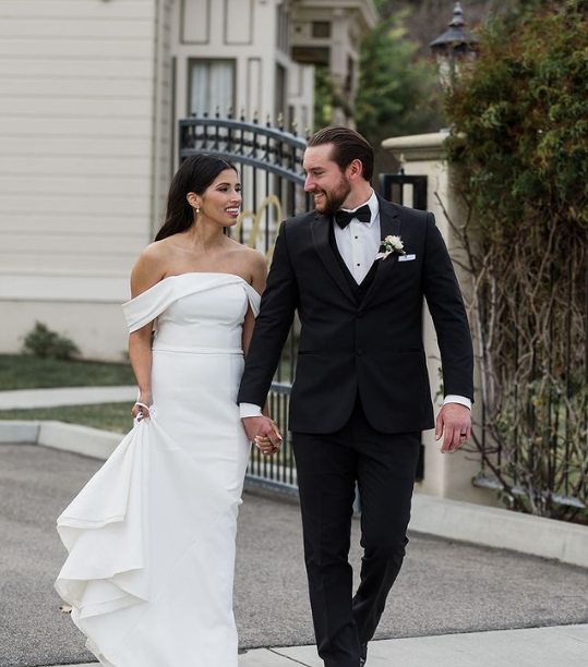 A bride and groom are walking down the street holding hands