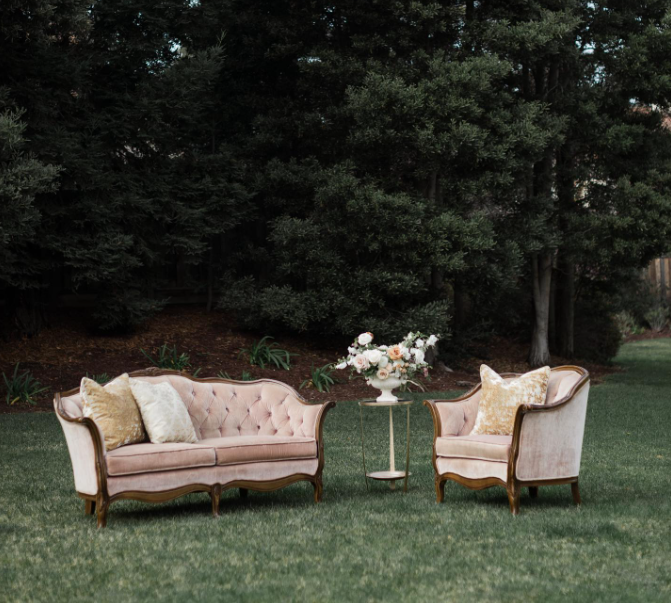 A couch and two chairs are sitting on a lush green field.