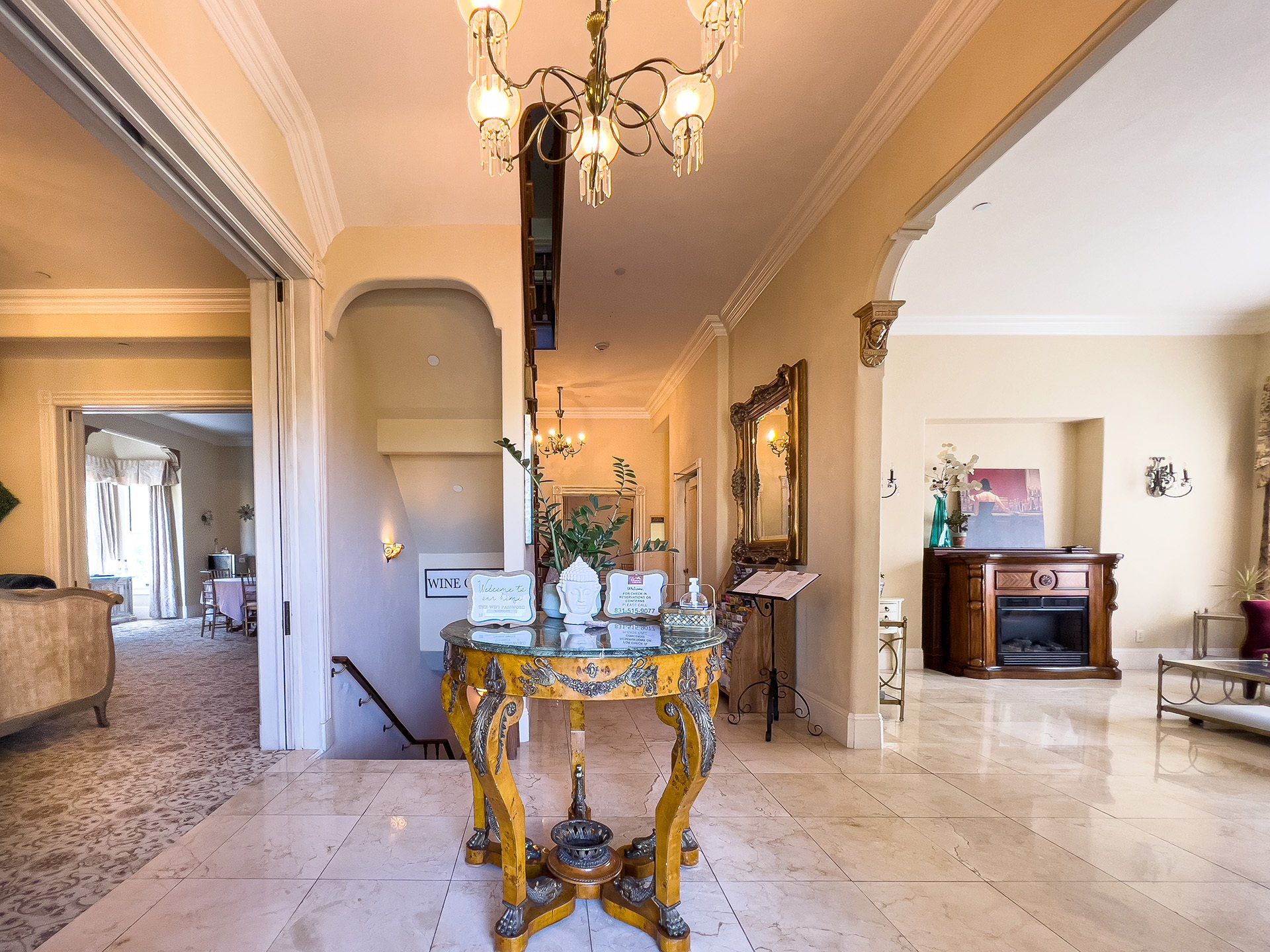 A hallway in a house with a table and a chandelier.
