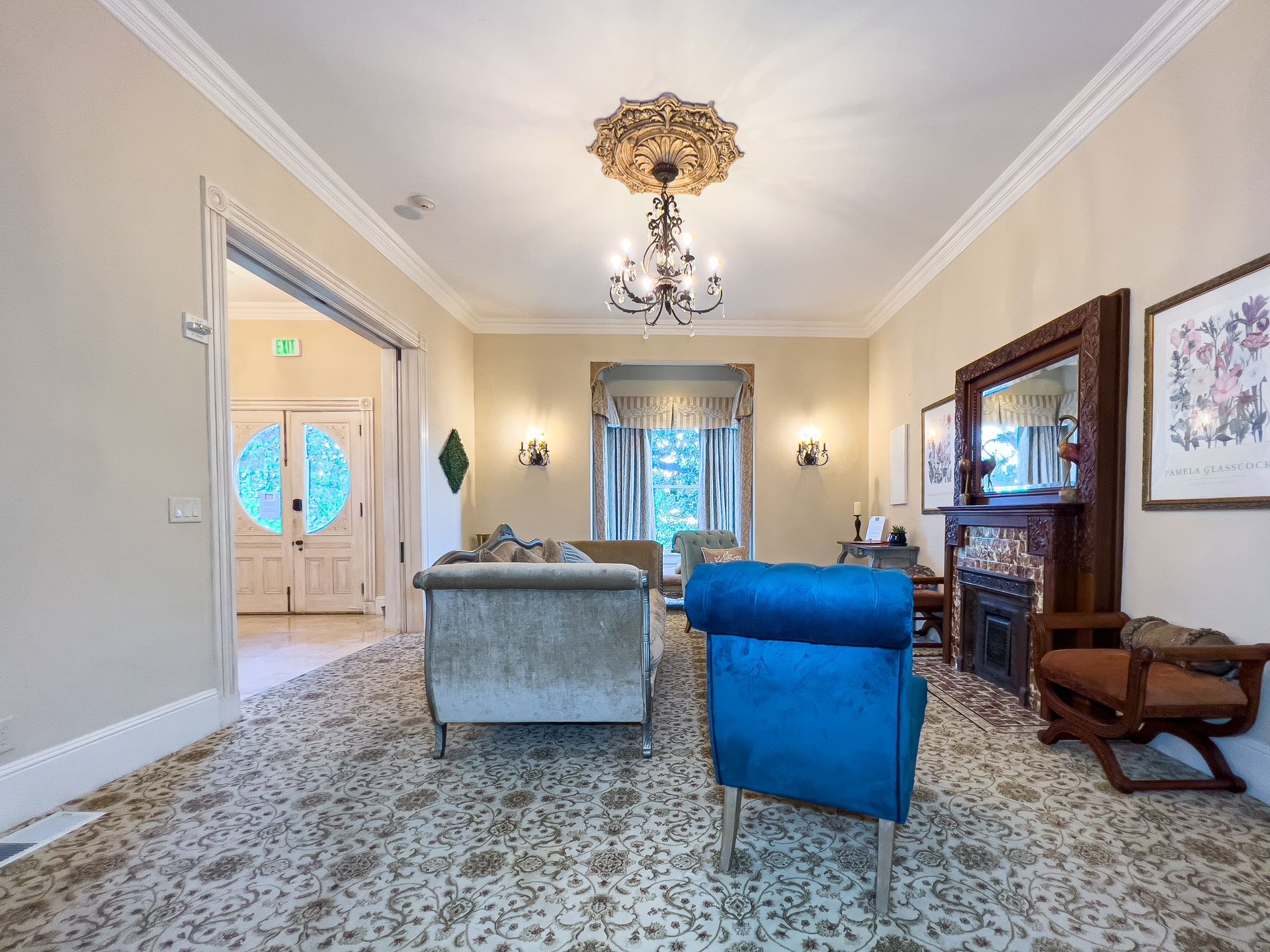 A living room with a couch , chair , fireplace and chandelier.