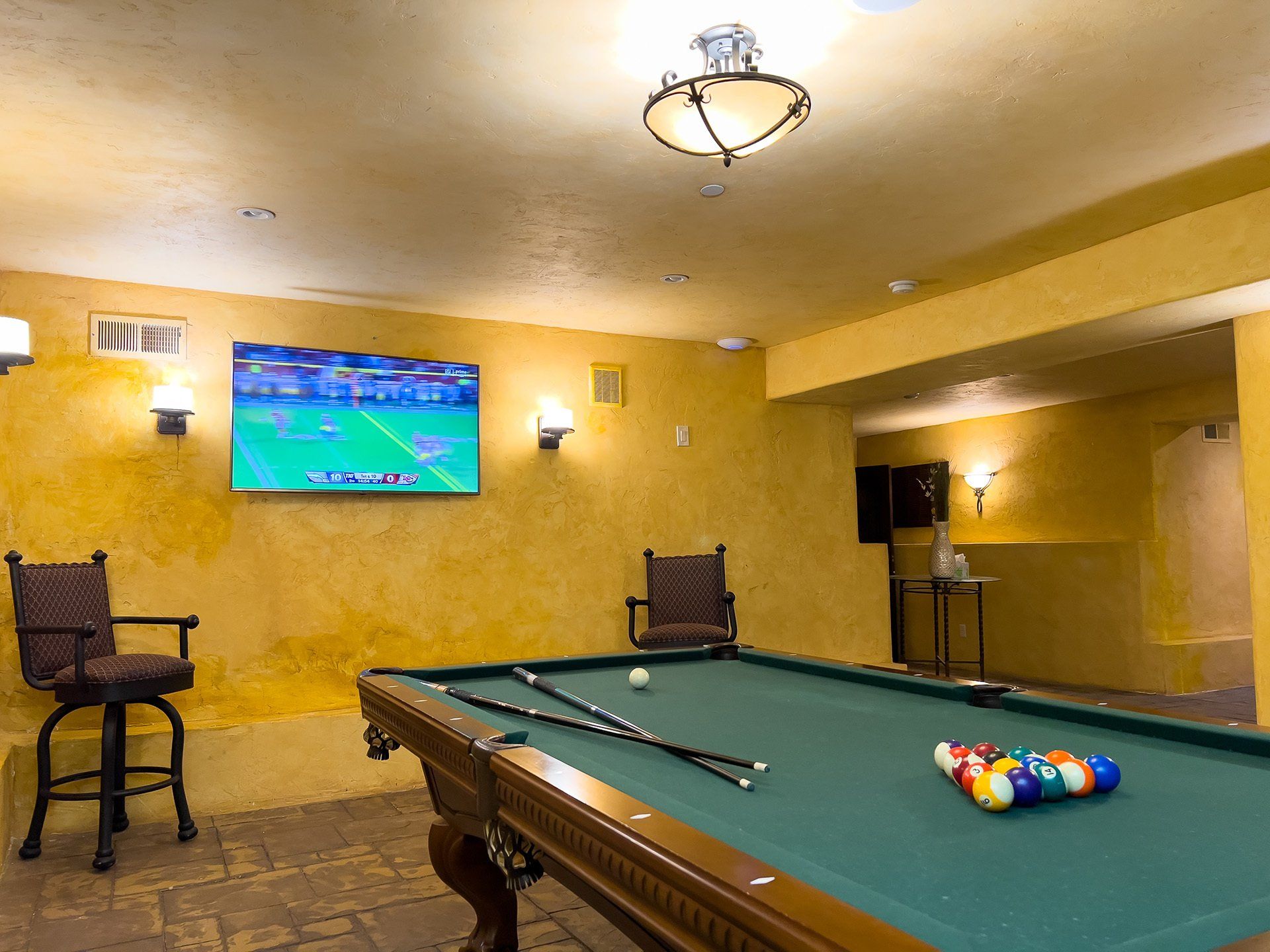 A pool table in a basement with a television on the wall.