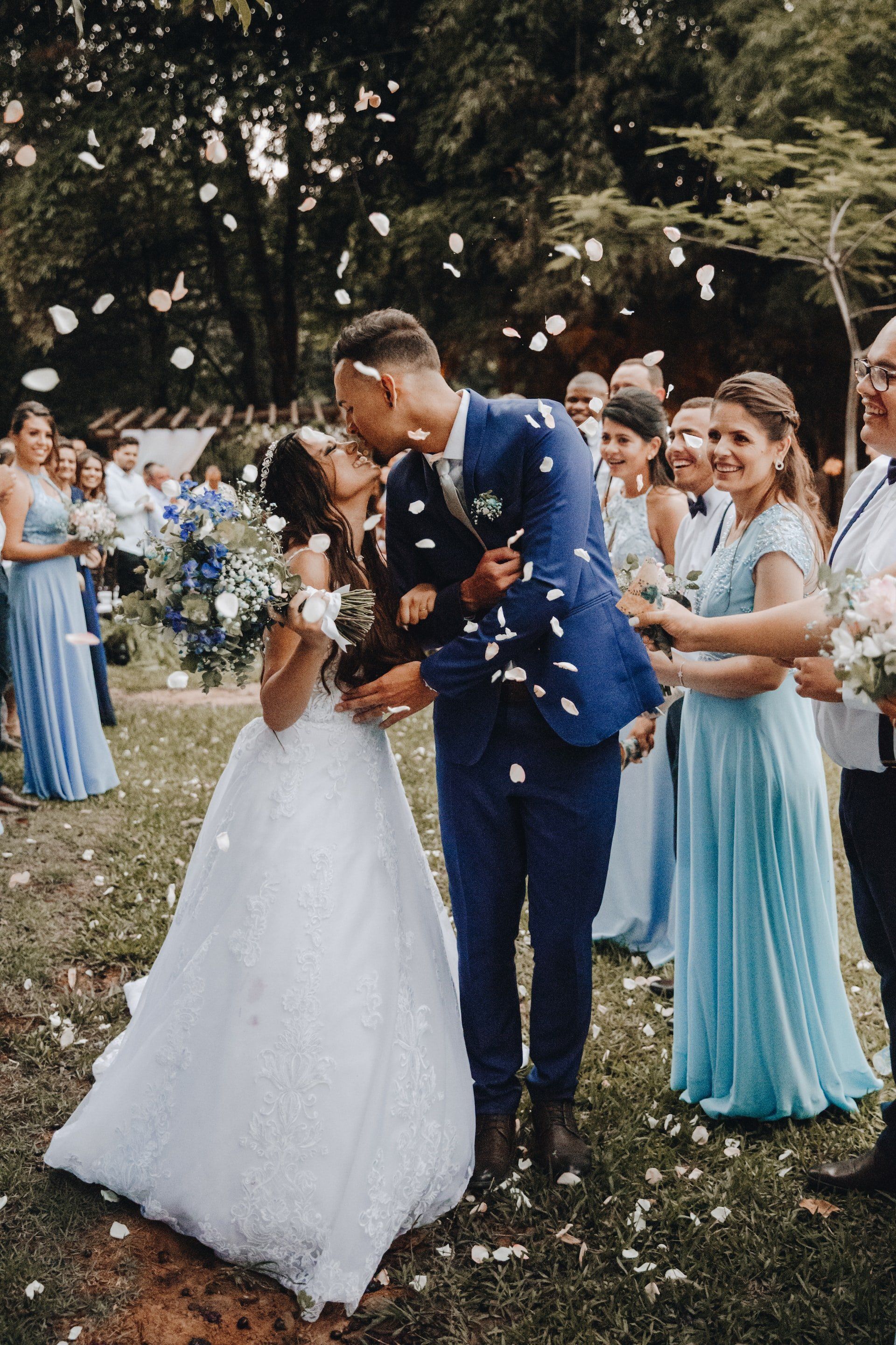A bride and groom are kissing in front of their wedding party.