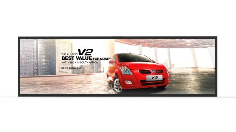 A red car is driving down a street in a parking lot.