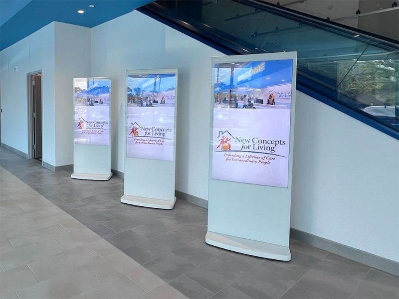 Three large screens are sitting next to each other in a hallway.