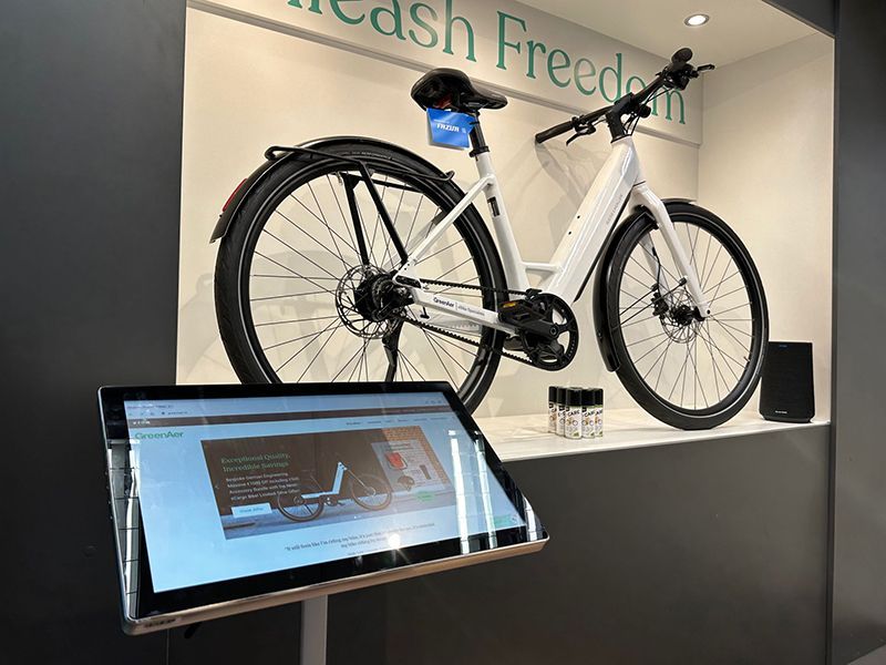 A bicycle is displayed in a display case next to a tablet.