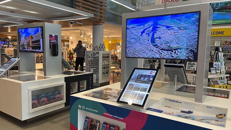 A store with a lot of televisions and a table with a tablet on it.