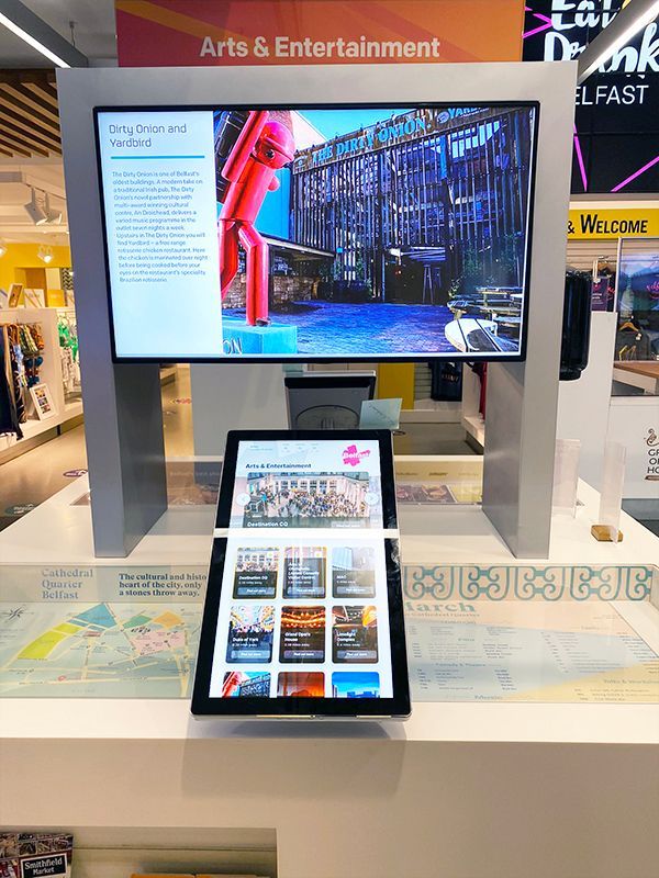 A large flat screen tv is sitting on top of a table next to a tablet.