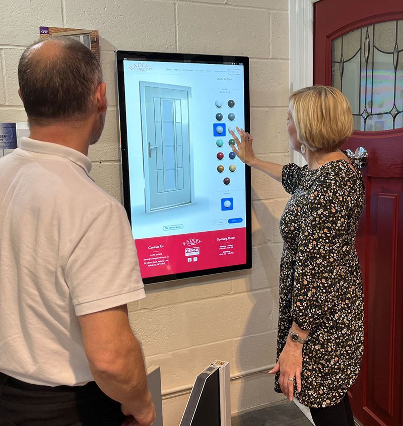 A man and a woman are looking at a door on a screen