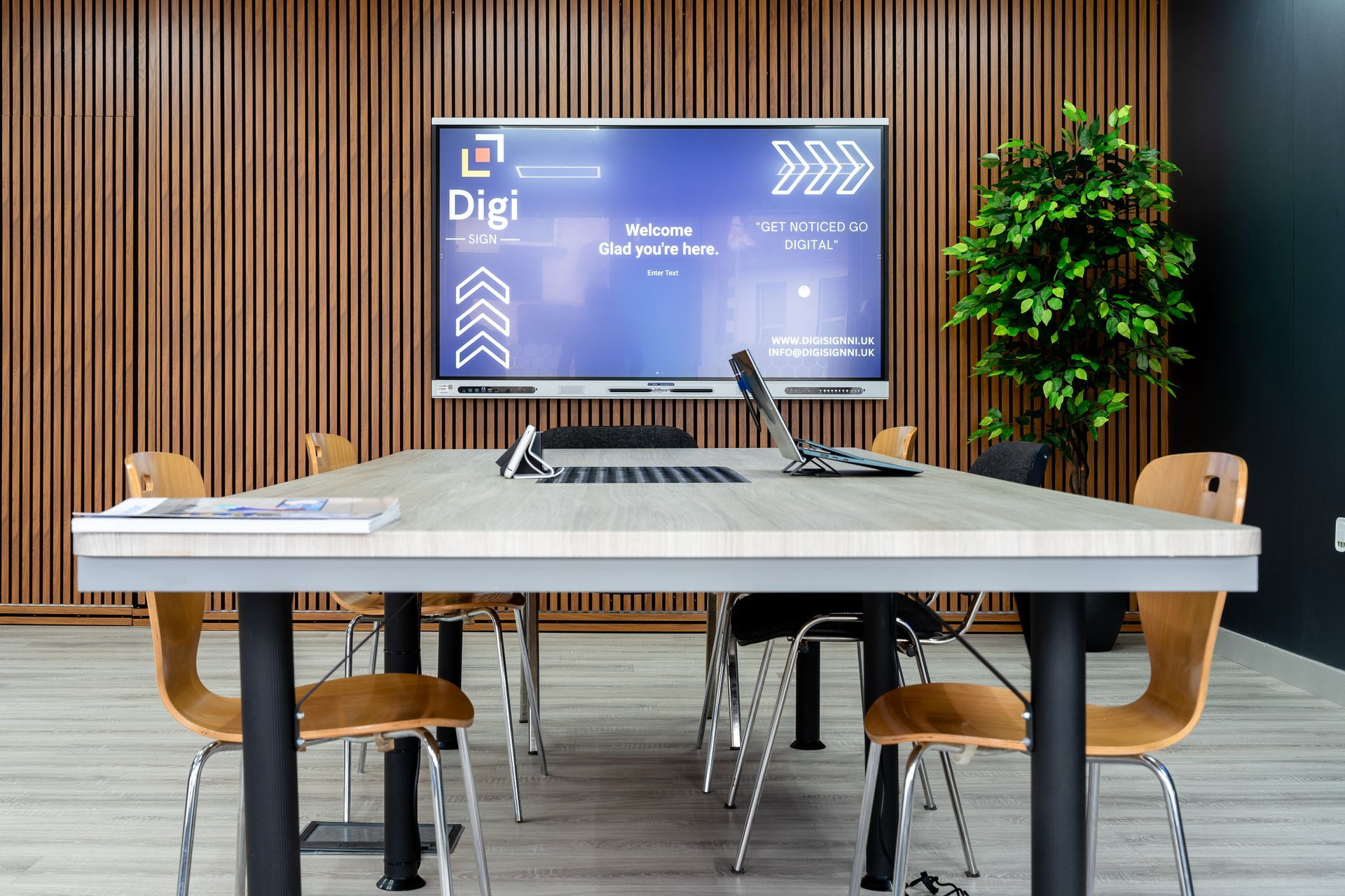 A conference room with a long table and chairs and a large screen on the wall.