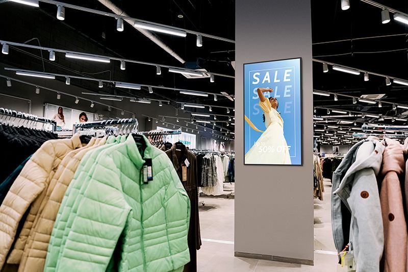There is a sale sign on the wall of a clothing store.