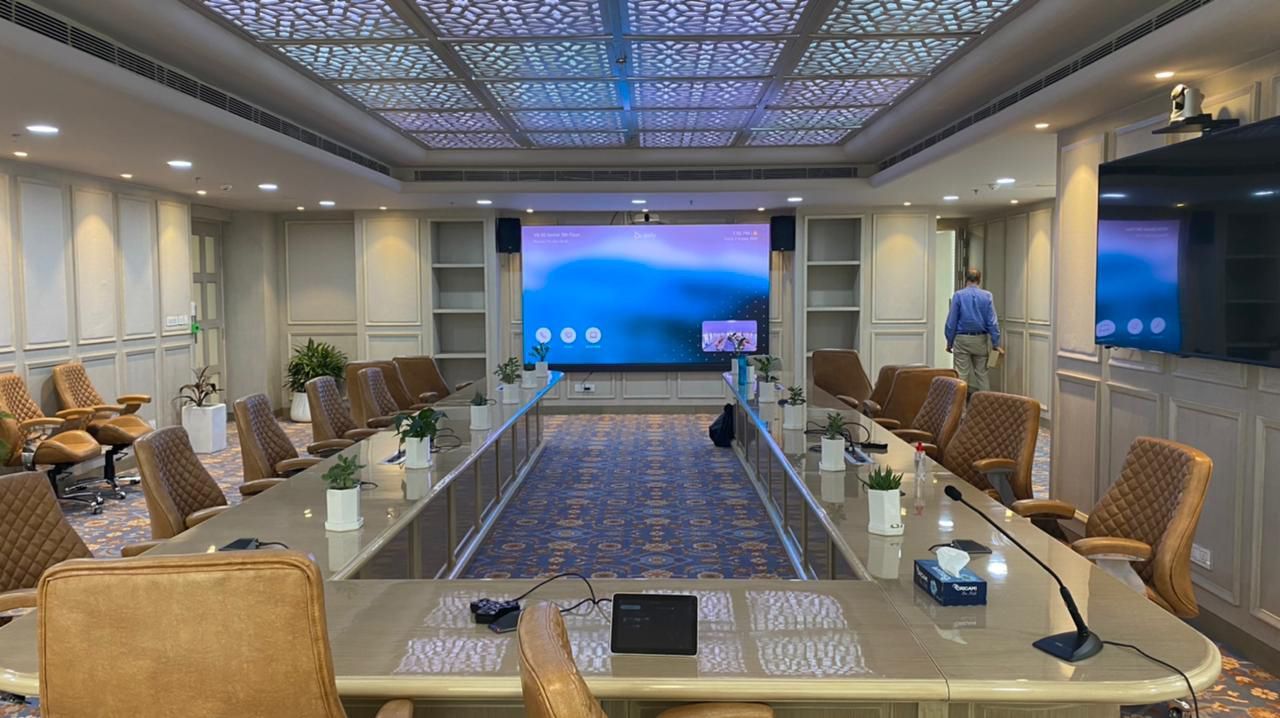 A large conference room with a long table and chairs and a large screen.