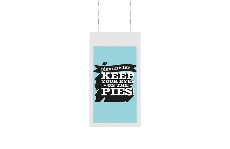 A poster that says `` keep your eye on the pies '' is hanging from a wire.