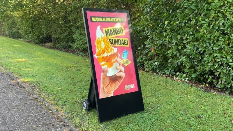 A sign that says mango sundae is sitting on the side of a road.