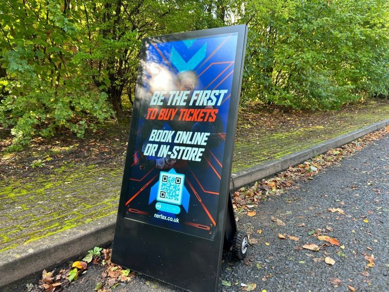 A sign that says `` be the first to buy tickets '' is sitting on the side of the road.