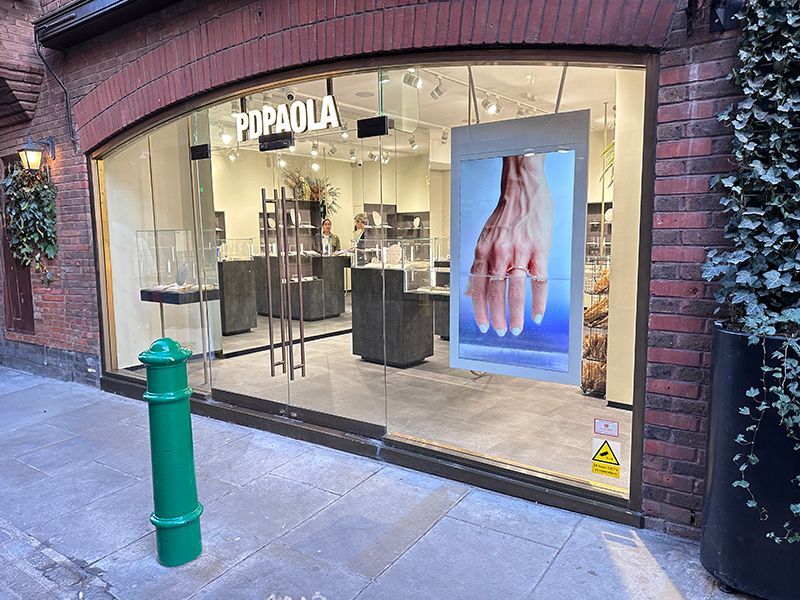 A store front with a green pole in front of it.