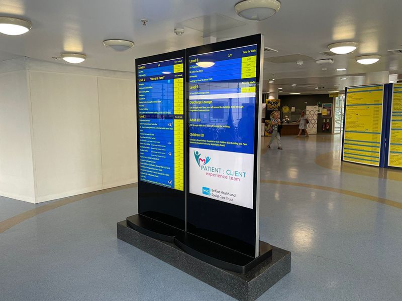 Two large screens are displayed in a hallway.