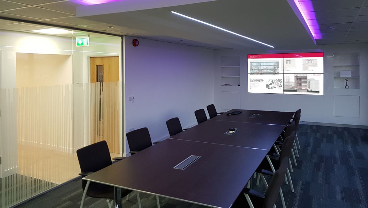 A conference room with a long table and chairs and a projector screen.