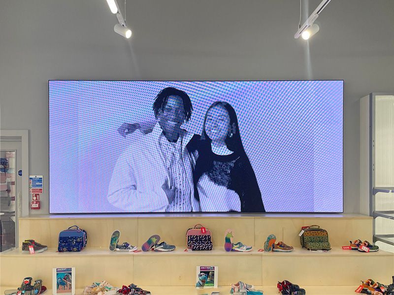 A man and a woman are standing next to each other in front of a large screen.