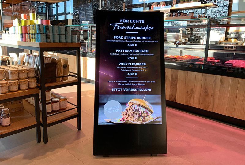 A sign in a restaurant with a picture of a hamburger on it.