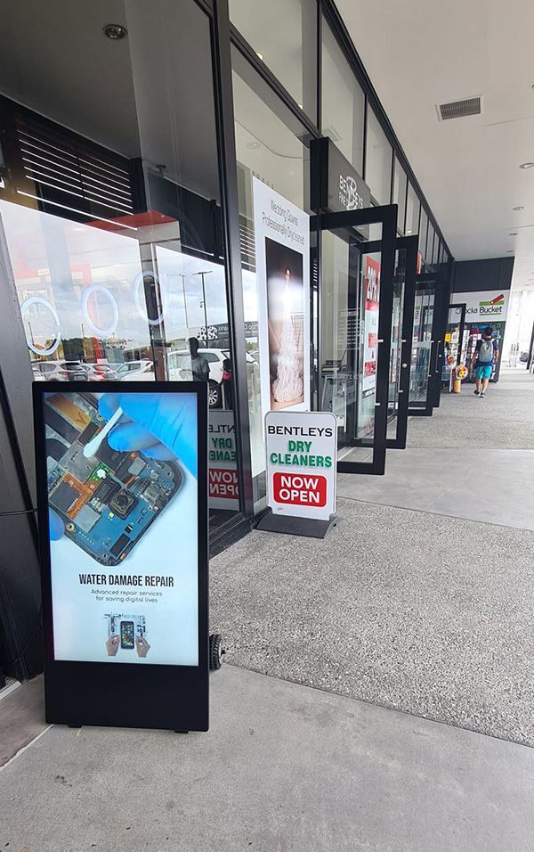 A row of store fronts with signs in front of them.