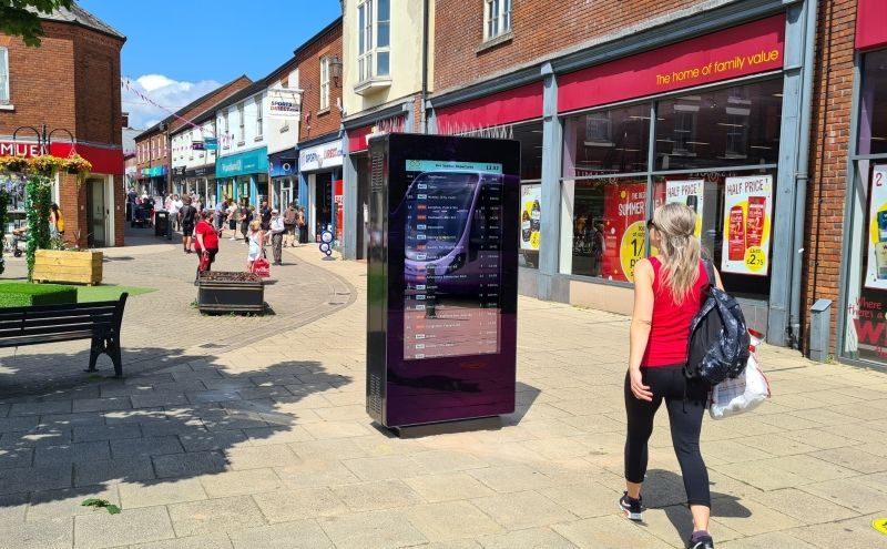 A woman is walking down a sidewalk in front of a store.
