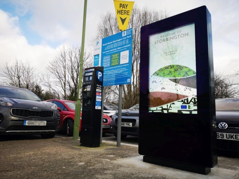 A parking lot with cars parked in front of a pay here sign.