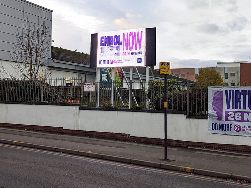 A billboard on the side of a road that says enroll now