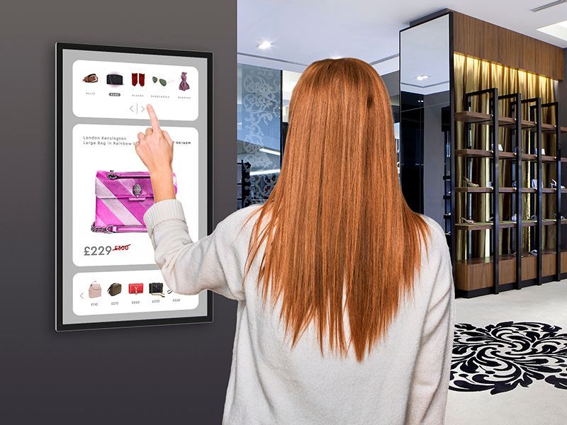 A woman is touching a screen in a store.