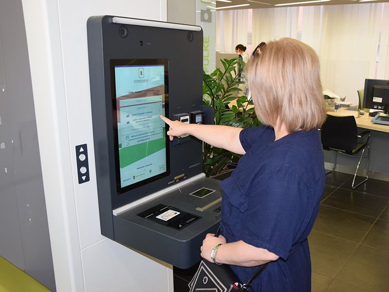 A woman is pointing at a screen on a wall.