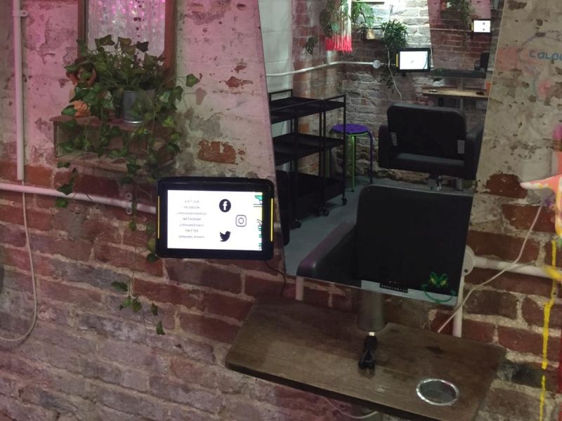 A tablet is sitting on a table in front of a brick wall.
