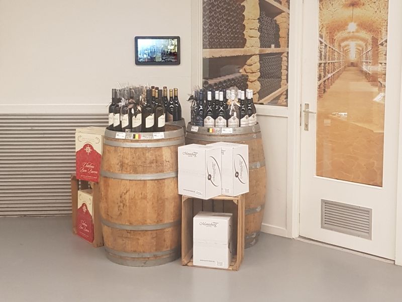 Two wooden barrels filled with bottles of wine in a wine cellar.