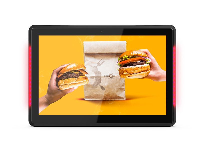 A person is holding a hamburger and a bag of hamburgers on a tablet.
