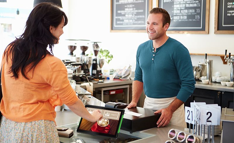 A man is serving a woman at a counter in a restaurant.