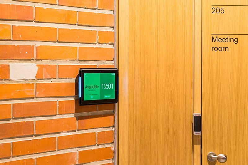 A brick wall with a wooden door and a meeting room sign on it.