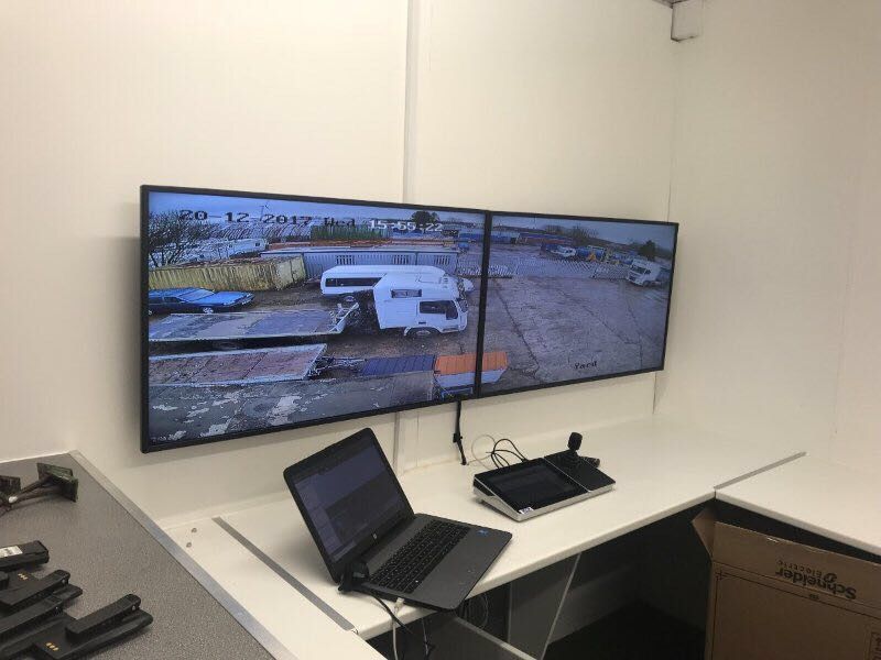 A laptop is sitting on a desk in front of two monitors.